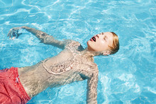 Teenager In Red Swimming Trunks Relaxes In The Pool