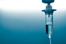 Close Up Of A Slow Intravenous Drip With A Blurred Lit Neon In The Background In A Hospital Room