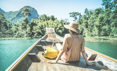 Young woman traveler on longtail boat trip at island hopping in Cheow Lan Lake - Wanderlust and travel concept with adventure girl tourist wanderer on excursion in Thailand - Retro turquoise filter