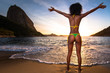 Sexy Brazilian Girl in Bikini Stands in the Beach With Open Arms and Welcomes A New Day in Rio de Janeiro With the Sugarloaf Mountain in the Background