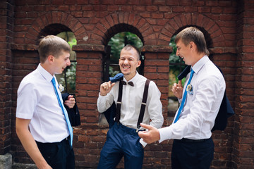 Canvas Print - The handsome groom  and  groomsmen laughing  near wall