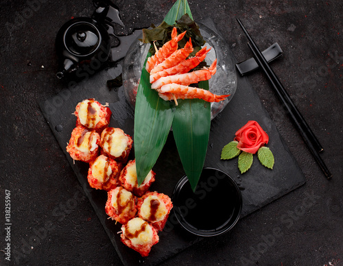 kuchnia-japonska-pieczone-sushi-rolls-i-krewetkowe-szaszlyki-na-kamieniu-na-czarnym-tle-betonu