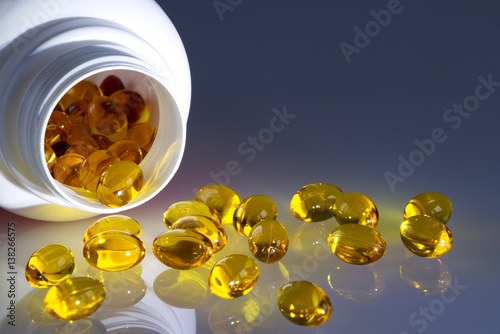 Fotografie, Obraz Omega 3 fish oil capsules spilled from a plastic bottle on a gradient background