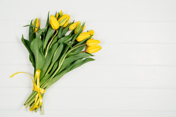 Poster - Background with yellow tulips on white wooden table top view. Creative woman's workspace concept with copy space. Product photograph taken from above with frame composition