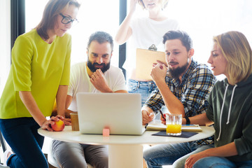 Project development team is brainstorming new concepts for the new business project promotion. Group of project managers is reading business news on a modern portable computer during leisure time.