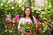 Pretty young florist with beautiful bouquet in greenhouse