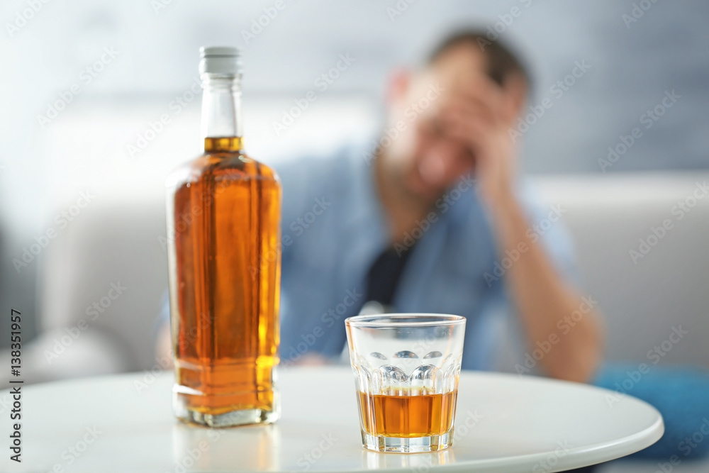 Bottle and glass of whisky on white table