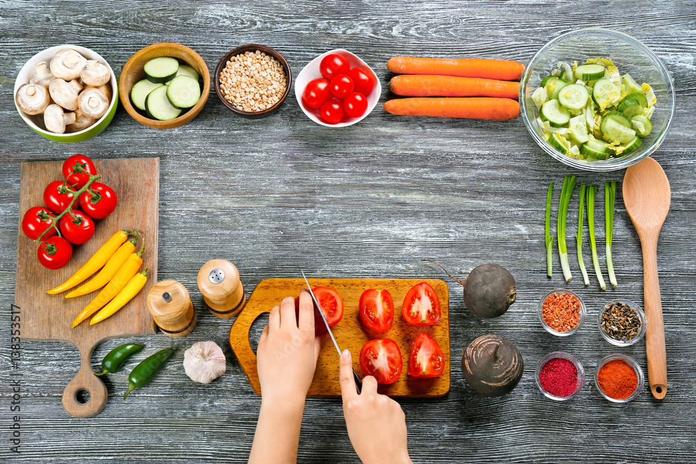 Female hands cutting tomatoes at table, top view