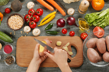 Poster - Female hands peeling potato at table, top view