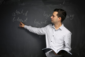 Canvas Print - Handsome young teacher explaining math formulas written on blackboard