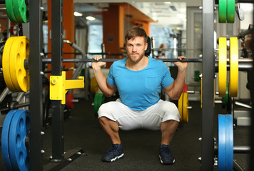 Wall Mural - Young handsome man with barbell training in gym