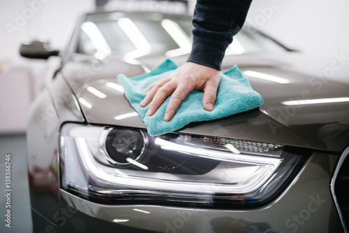 Plakat Człowiek czyszczenia samochodu z tkaniny z mikrofibry, samochód szczegółowo (lub valeting) koncepcja. Selektywna ostrość.