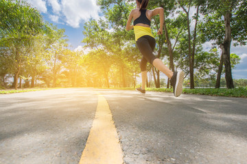 Wall Mural - Back view of young fitness woman running on the road in the morning. People and sport concept