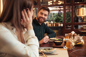 Sticker - Cheerful young loving couple sitting in cafe and eating