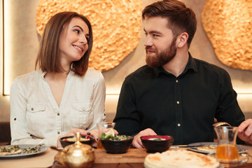 Sticker - Smiling young loving couple sitting in cafe and eating.