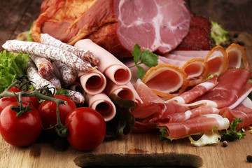 Food tray with delicious salami, pieces of sliced ham, sausage, tomatoes, salad and vegetable - Meat platter with selection