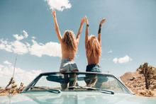 Rear View Of Women Topless In Convertible Car Arms Raised