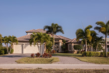 Typical Southwest Florida Concrete Block And Stucco Home In The Countryside With Palm Trees, Tropical Plants And Flowers, Grass Lawn And Pine Trees. Florida