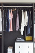 © worldwide_stock - modern closet with row of cloths hanging in black wardrobe