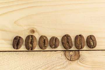 Brown coffee beans on yellow textured wooden board background close up.