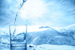 concept purity of blue water in transparent glass over winter landscape of mountains higher than clouds, close up