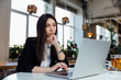 © photominus21 - Young business woman sitting at table in cafe, . Working with the notebook and glass of tea.