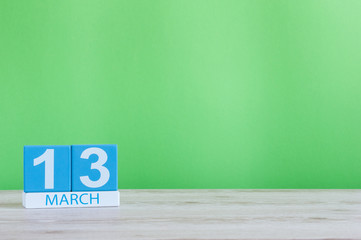 Wall Mural - March 13th. Day 13 of month, daily calendar on table and green background. Spring time, empty space for text