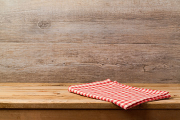 Wall Mural - Empty wooden deck table with checked red tablecloth over wooden wall background for product montage display