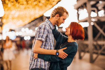 Happy couple embracing in the evening on a light garlands