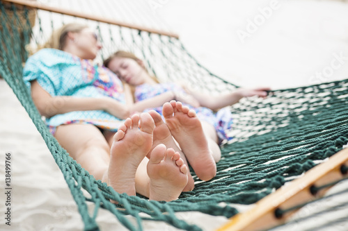 Fotografie, Obraz Barefoot and Relaxed family napping in a hammock together outdoors on a sunny day