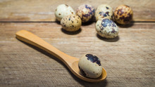 Boiled Partridge Egg In A Spoon And On Wooden Desk