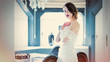 © Masson - beautiful young woman standing near the table in the light luxury room