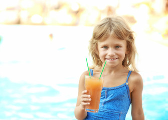 Little girl with cocktail at swimming pool on sunny day