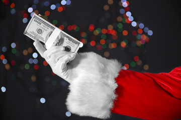 Poster - Santa Claus hand holding money on blurred lights background