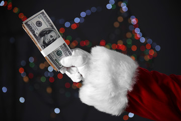 Sticker - Santa Claus hand holding money on blurred lights background