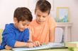 © Africa Studio - Cute little boys with book sitting at table, closeup