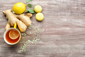 Poster - Cup of tea with lemon, ginger and macaroons on wooden background