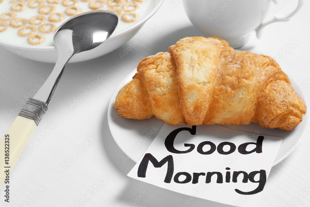 Note with phrase GOOD MORNING and breakfast on table, closeup
