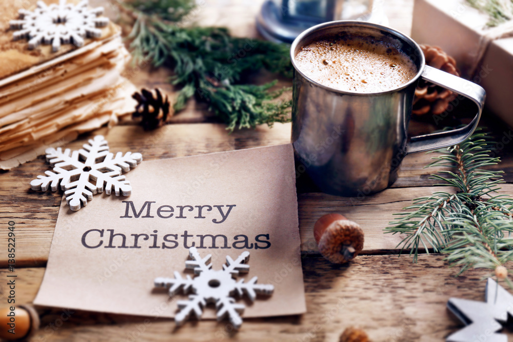 Cup of cocoa with greeting card on wooden background