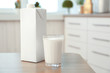 Carton box and glass of milk on table in kitchen