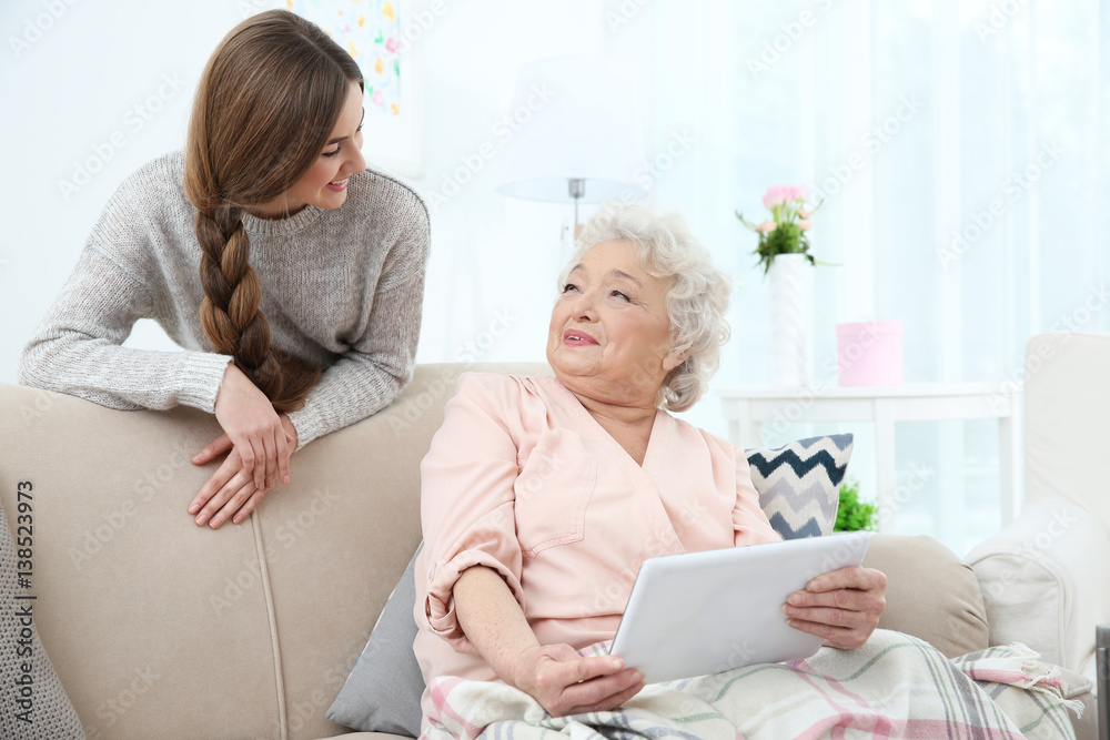Beautiful girl with grandmother using tablet at home