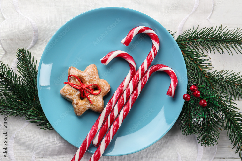 Plate with candy canes and Christmas decorations on napkin