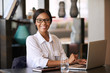© nakophotography - Beautiful young black woman smiling at camera while seated behind her personal computer, where she was working on managing her finances for the upcoming tax period and making online payments.