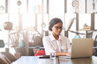 © nakophotography - Professional black entrepreneur and businesswoman busy working on her laptop computer while seated at the head of the conference table in the business lounge.