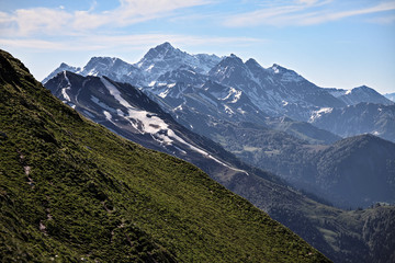 Wall Mural - Beautiful scenic landscape of snow covered mountain peaks in Caucasus mountains at spring on a sunny day with blue sky and clouds