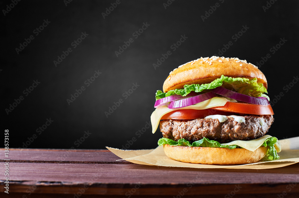 Craft beef burger on wooden table isolated on black background. - obrazy, fototapety, plakaty 