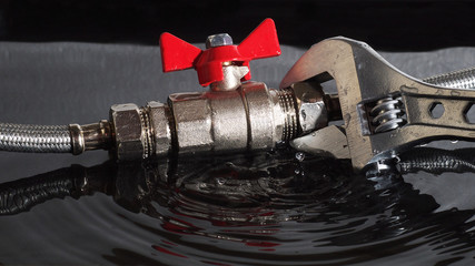 assembled flexible fittings, ball valve, union and adjustable wrench in water with falling drops and