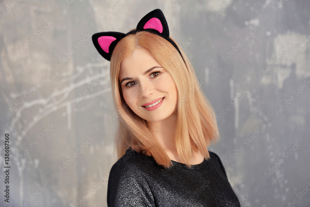 Beautiful young woman with cat ears on grunge background