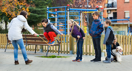 Wall Mural - Positive kids playing in jump rope game