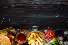 Fresh Delicious Burgers With French Fries, Sauce And Drink On The Wooden Table Top View, With Copy Space